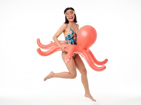 Young Woman in Swimsuit Jumps with Inflatable Octopus and Goggles Ready for Summer Fun Isolated on White Background