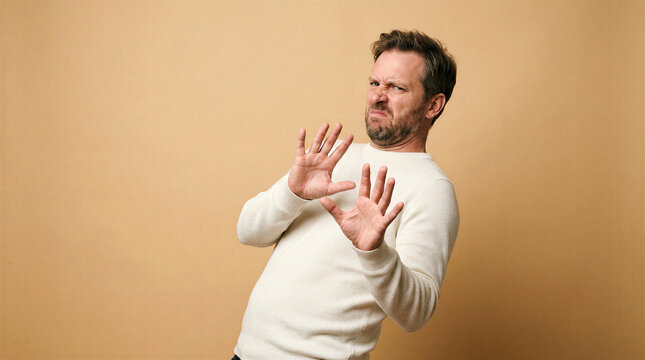 Man recoiling defensively with hands up in a studio setting