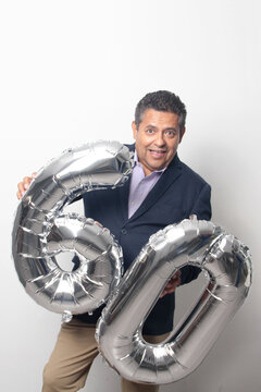 60-year-old Latino man with a dark skin displays 60 shaped balloons to celebrate his birthday and his entry into his old age