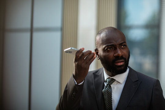 Businessman using smartphone speakerphone outside office building