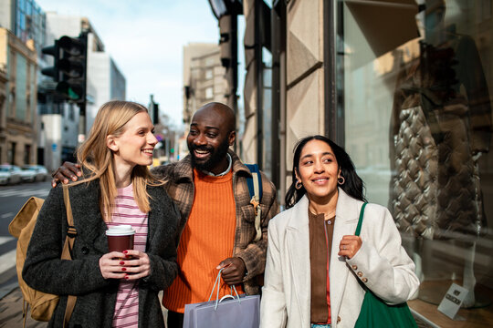 Three friends shopping and walking on a city street