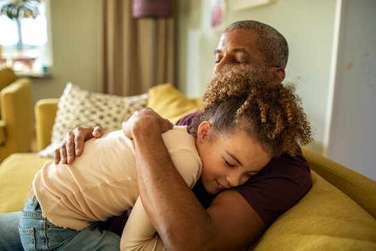 Father hugging daughter on sofa at home