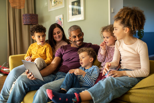 Parents and children watching tablet on the couch at home