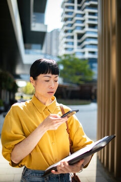 Businesswoman using voice assistant on smartphone in city