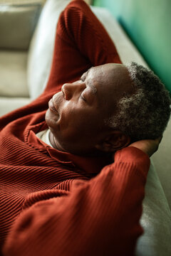Senior man napping on home sofa