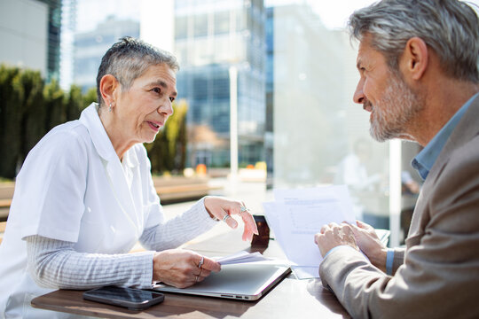 Senior professionals meeting outdoors with documents in city