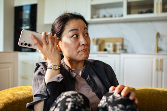 Middle-aged woman reacting to phone call in home kitchen