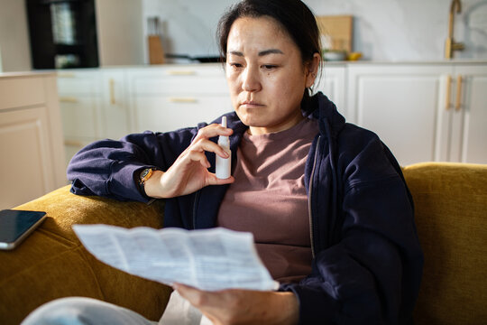 Woman reading nasal spray instructions at home