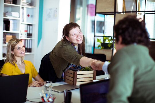 Smiling new employee shaking hands with colleague in modern office