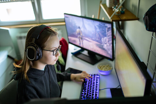 Teen girl gaming on pc with headset at home desk