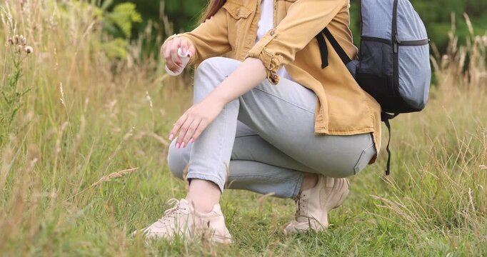 Woman spraying insect repellent onto her leg outdoors, closeup