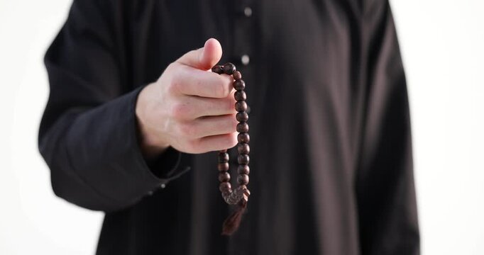 Priest in cassock with rosary praying on white background, closeup