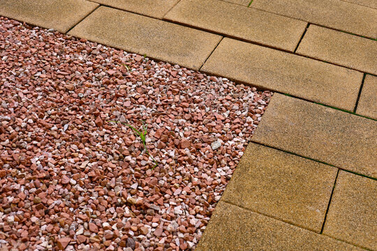 Red crushed rock border next to stone pavement tiles.