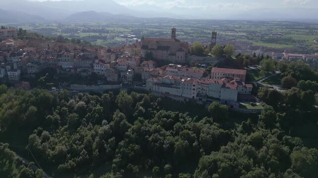 Mondov&igrave; hilltop old town and medieval bell tower aerial view, tilting up to reveal new town and scenic Italian landscape in background, Piedmont