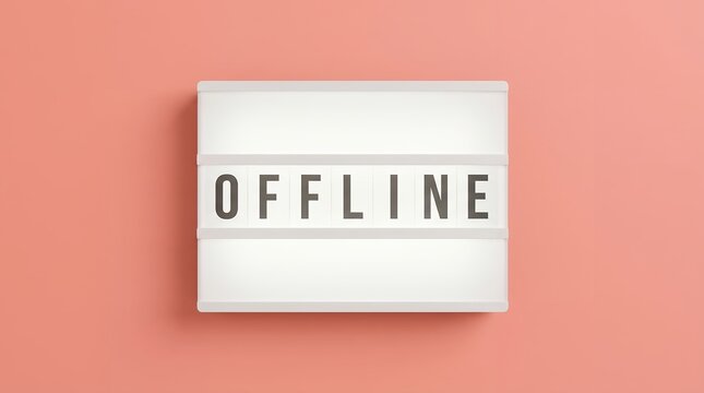 Illuminated sign displaying the word OFFLINE in capital letters against a solid coral pink surface creating a simple yet impactful visual statement disconnected not online