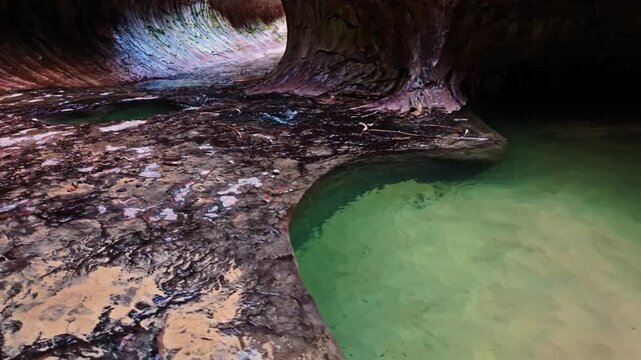 Pristine creek waters carve through sculpted sandstone pools within the tubular chambers of The Subway in Zion National Park Utah