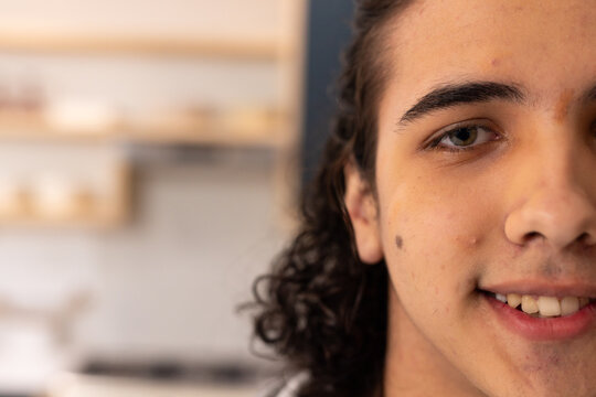 Adult male smiling and facing camera in kitchen, showing mole, blurred jars and stovetop