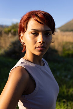 Woman standing in grassy meadow in warm golden sun wearing sleeveless ribbed top