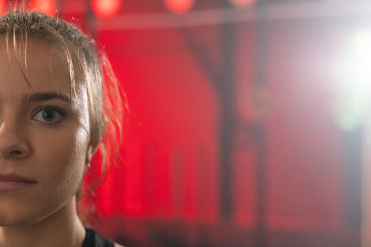 Female posing in gym showing left half face wearing black top with metal rig, copy space