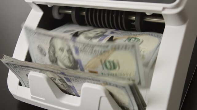 Money counting machine processing dollars bills in motion. Business finance theme. Device counting paper money in motion. Counting cash concept. Banking operation.