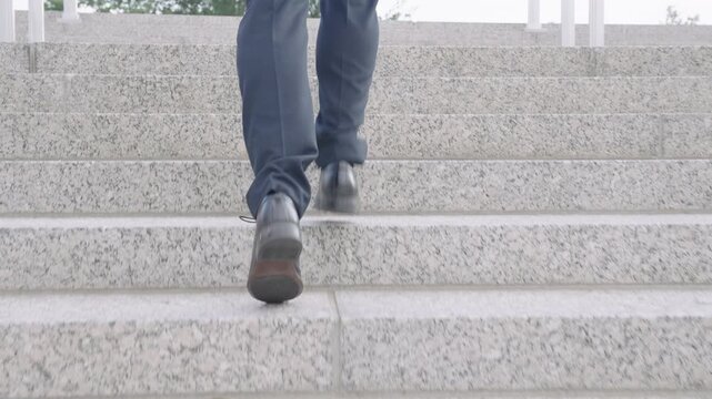 Businessman moving up stairs confidently. Business man walking steps toward business success. Businessman climbing stairs with clear goal. Business man taking each step in career.