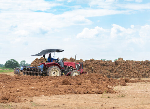 Farmer driving a tractor preparing the land and turning soil for agricultural planting during daytime.