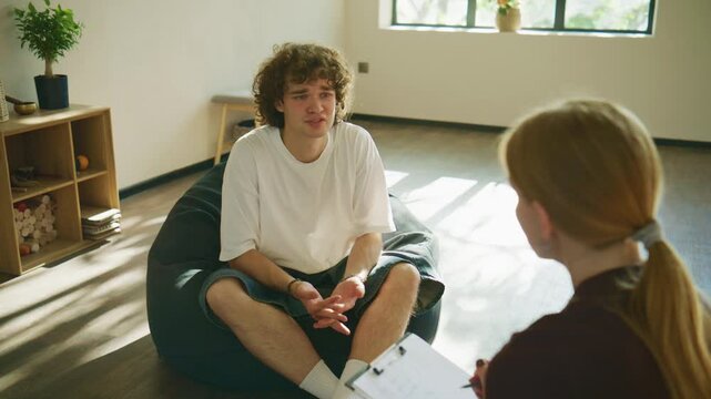 A male client sits in therapy, visibly distressed, as he shares his emotions with the psychologist, highlighting vulnerability and openness