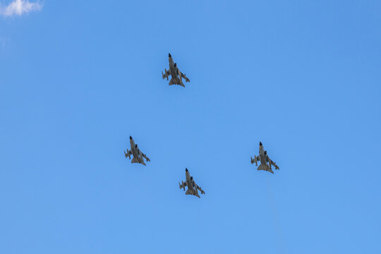 Military fighter jets flying formation in a clear blue sky during an aerial display