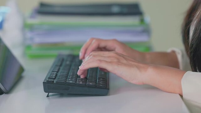 Close-up of hands typing on a computer keyboard in an office