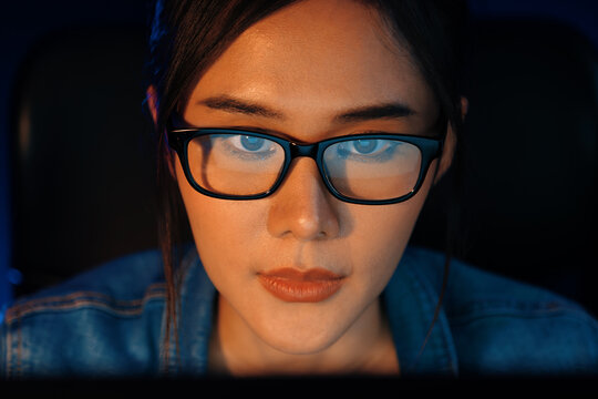 Portrait young beautiful Asian creative with glasses of serious face looking on pc to search project creator social media online, planning strategy creator at neon modern office at night. Stratagem.
