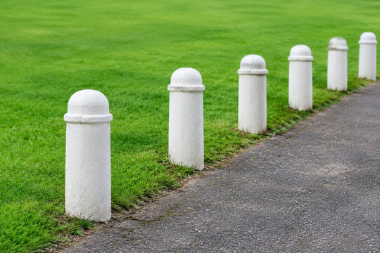 Row of white stone bollards and manicured lawn, boundary and landscaping concept