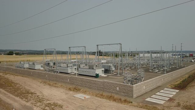 Electrical substation beside data centers in Hillsboro, Oregon, showing high-voltage equipment in the Silicon Forest technology corridor, drone orbit.