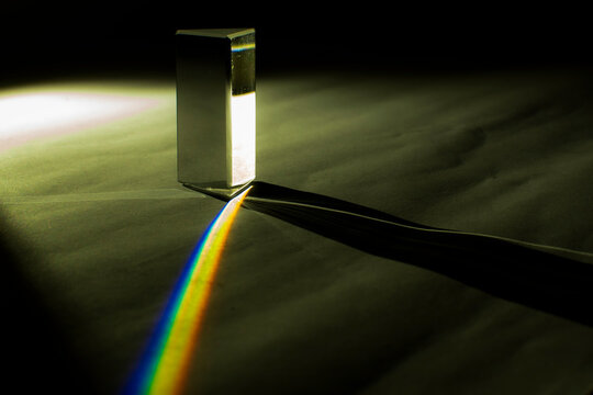 Glass prism creating a vivid rainbow beam and long geometric shadow