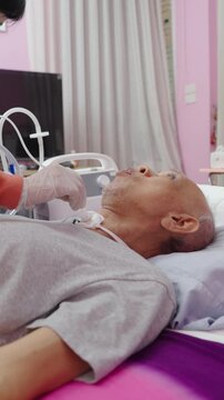 Nurse suctions mucus from a tube in the throat of a patient who had a tracheostomy and is recovering at home