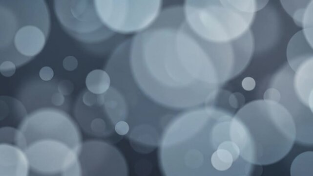 Atmospheric steel blue and gray bokeh circles move smoothly through layered parallax depth with cool diffused light, creating an energetic futuristic abstract background loop.