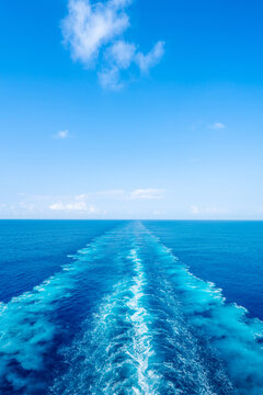 Water wake trail left by cruise ship in deep blue ocean under clear sky with copy space