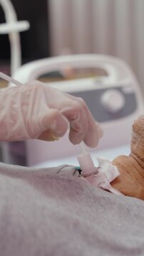 Close-up Hand of nurse suctions mucus from a tube in the throat of a patient who had a tracheostomy and is recovering at home