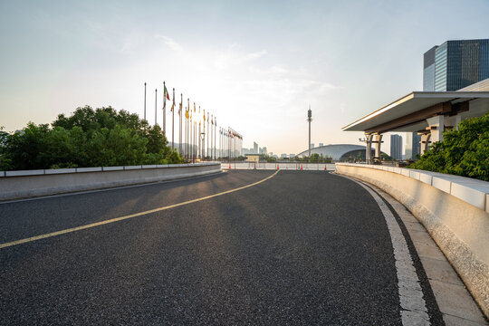 city road extending towards modern buildings under clear morning sky