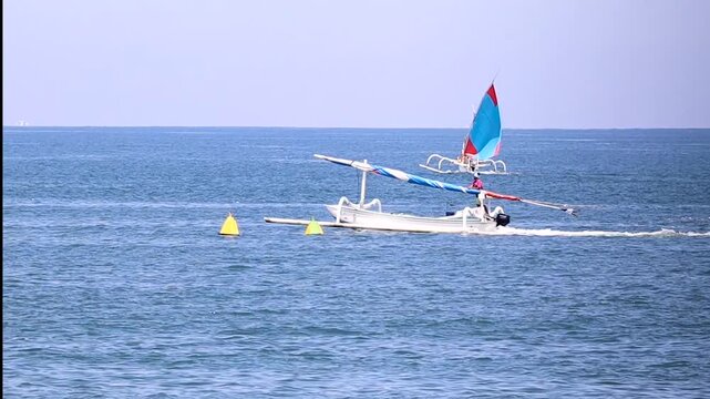 Traditional Jukung Sailboat and Motorboat Crossing on Blue Sea at Teluk Waru Lombok