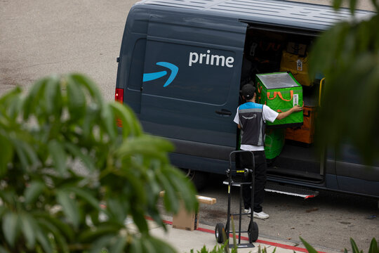Fullerton, California, USA - September 6, 2026: An Amazon worker opens the side of a delivery van.