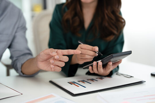 Close up hands of businessman financial advisor explaining financial result showing calculator to client or Colleague in meeting.