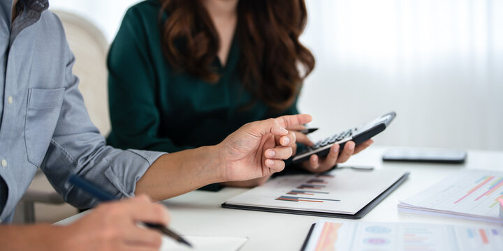 Close up hands of Two colleagues engaged in business analytics, over financial charts. Colleagues Collaborating on Business Analytics