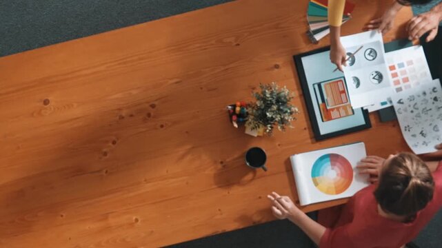 Top aerial view of business people working together to choosing color from color palette. Manager present idea by using tablet to marketing team while business man looking at logo graphic. Symposium.