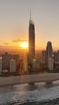 Sunset behind the Q1 tower on the Gold Coast, aerial drone footage over Surfers Paradise, Queensland Australia - vertical video