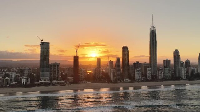 Surfers Paradise skyline at sunset seen from over the ocean, aerial drone footage, Gold Coast, Queensland Australia