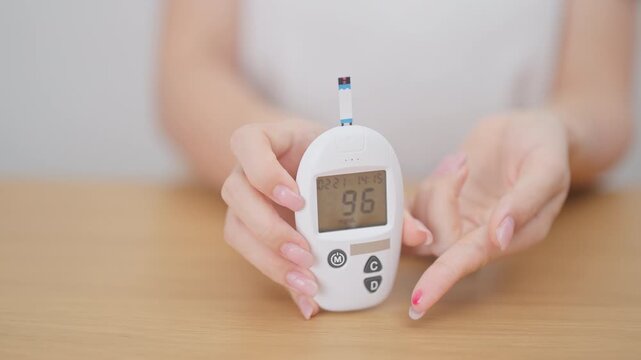 Hand using lancet pen on finger with Blood drop glucose testing or Diabetes checking by digital blood glucose meter. blood sugar level, Diabetes Day, Glycemia, Hypoglycemia, Hyperglycemia and insulin