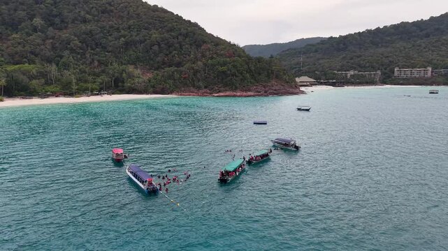 Aerial view of boats with tourists snorkeling in clear tropical blue ocean waters near a coastal beach