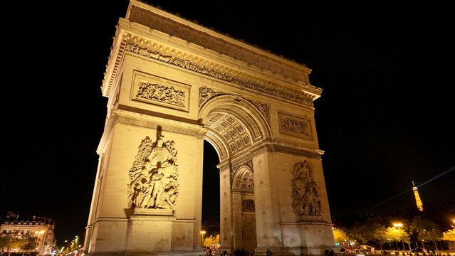 Arc de Triomphe standing brightly illuminated against a dark sky in Paris
