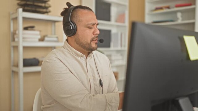 Man call center agent with headset writing in red notebook, pen in hand while talking at desk in a building; concentration diligence.