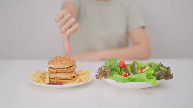 woman with Hamburger and thumbs down, Rejecting and refusing.Healthy and Unhealthy Food Choice, Calories and Nutrition of vegetables Salad and Hamburger. dieting, weight loss, junk food and lifestyle
